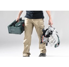 Person trägt eine Kapp- und Gehrungssäge sowie einen Werkzeugkoffer