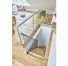 Innenansicht eines Hauses mit einer Holztreppe, einem Glasgeländer und einer hellen Einrichtung.