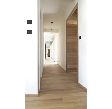 Flur mit Holzboden, weißen Wänden und minimalistischen Pendelleuchten