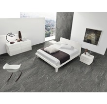 Helles Schlafzimmer mit Doppelbett, Nachttisch, Kommode und Sessel auf grauem Fliesenboden