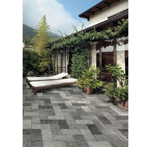 Terrasse mit Fliesen in Steinoptik, Liegestühlen und Bepflanzung vor einem Haus