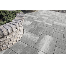 Pflastersteine mit Natursteinmauer im Garten