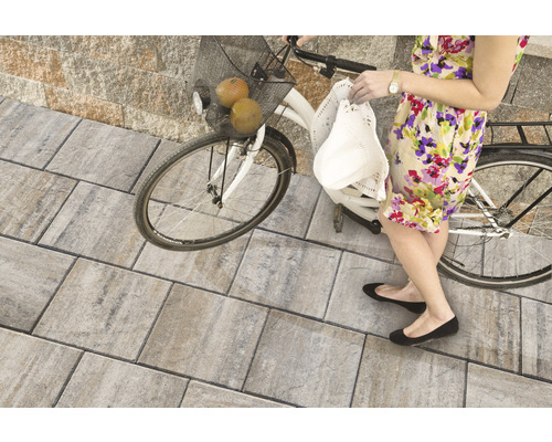 Frau mit Fahrrad auf Pflastersteinen