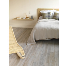 Schlafzimmer mit Bett, Nachttisch und Korbsessel auf Holzboden