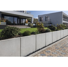 Garten mit Betonstützmauer und Pflasterweg vor modernen Häusern