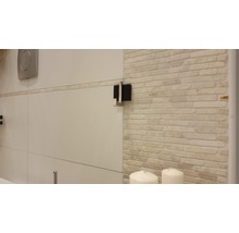 Detailansicht eines Badezimmers mit Fliesenwand und Sanitärobjekten