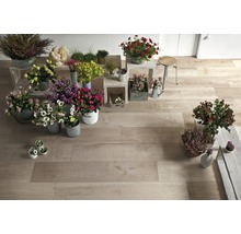 Innenraum mit Holzboden und Blumenarrangements auf Tischen und Hockern