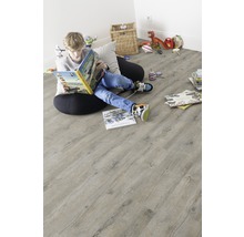 Ein Junge liest ein Buch auf einem hellen Holzboden im Kinderzimmer.