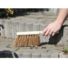 Hand fegt mit einer Kehrbürste eine Steintreppe