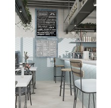 Innenansicht eines Cafés mit Tischen, Stühlen, Bar und einer Tafel mit Kreideaufschrift.