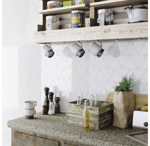 Küchenszene mit Wandfliesen in Dreiecksform, Holzregal und Küchenutensilien auf der Arbeitsfläche.