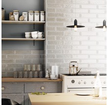 Küchenszene mit Fliesenwand, Regalen, Geschirr und Kochutensilien.