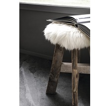 Hocker aus Holz mit Fellauflage und aufgeschlagenem Buch