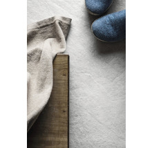 Hausschuhe neben gefalteter Textilie und Holzbrett