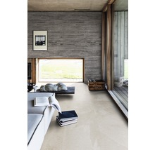 Heller Raum mit Sofa, Couchtisch, Büchern und keramischen Bodenfliesen.