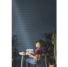 Frau arbeitet am Laptop vor einer Wand mit dreidimensionalen Fliesen