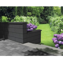 Gartenlandschaft mit einer Mauer aus Betonsteinen und Blumenbeeten