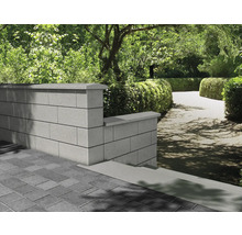 Gartenlandschaft mit Mauer aus Betonsteinen und gepflastertem Boden.