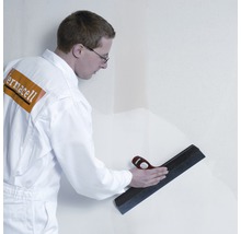 Handwerker glättet Wand mit Flächenspachtel