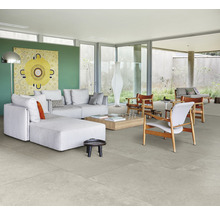 Helles Wohnzimmer mit grauen Bodenfliesen, Couch und Kunstwerk