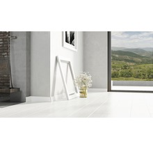 Heller Raum mit weißem Holzboden, zwei Bilderrahmen und einem Blumenstrauß.