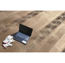 Verlegung von Bodenfliesen in Holzoptik mit Laptop und Arbeitshandschuhen