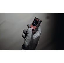 Eine Hand mit Arbeitshandschuh hält einen Laser-Entfernungsmesser.