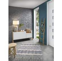 Wohnraum mit Steinwand, Kommode, Lampe, Teppich und Holzleiter