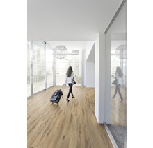 Heller Raum mit Laminatboden und einer Frau mit Rollkoffer