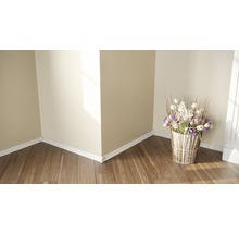 Raumecke mit Holzboden, weißen Sockelleisten und einem Blumenarrangement in einem Korb