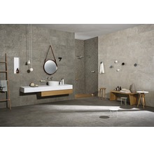 Badezimmer mit grauen Fliesen, Waschtisch mit Spiegel und Holzelementen, Bank und Hocker.