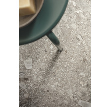 Detailaufnahme einer Bodenfliese mit Steindekor und einem Tischbein