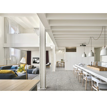 Helles Wohnzimmer mit grauen Bodenfliesen, Sofabereich und Essbereich mit langem Tisch