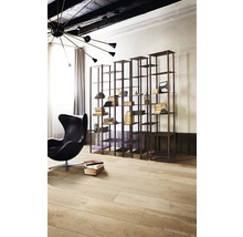 Innenaufnahme eines Wohnzimmers mit einem schwarzen Sessel, einem Bücherregal und einem Holzboden.