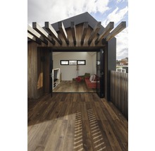 Blick von einer Holzterrasse in einen Wohnraum mit hellen Wänden und Möbeln