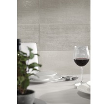 Wandfliesen über einem Esstisch mit Geschirr und Weinglas.