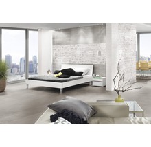 Heller, moderner Schlafraum mit Fliesenboden, weißem Bett und großem Fenster mit Stadtblick.