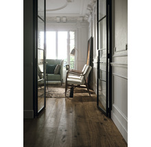 Heller Raum mit Holzboden, Sofa, Sessel und Glastüren.