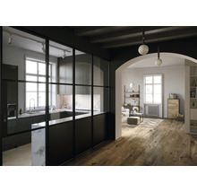 Helle, geräumige Wohnung mit Küche und Wohnzimmer, getrennt durch eine schwarze Glastrennwand.