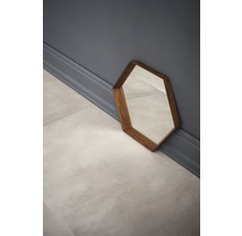 Sechseckiger Spiegel mit Holzrahmen steht an der Wand.