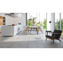 Helle Küche mit Kochinsel, Esstischgruppe und Sessel auf Fliesenboden.