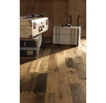 Dekorativer Holzboden mit aufgestapelten Vintage-Reisekoffern vor Holztüren