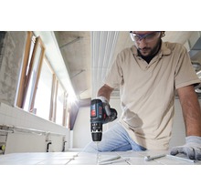 Handwerker bohrt mit einer Bohrmaschine ein Loch in eine Fliese.