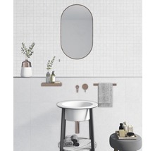 Helles Badezimmer mit Waschbecken, Spiegel und Ablageflächen.