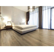 Heller Schlafzimmerraum mit Laminatboden, Bett, Vorhängen und Nachttischlampe.