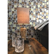 Dekorativer Tisch mit Lampe, zwei Gläsern und Flaschenöffner vor Mosaikwand