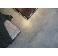 Detailaufnahme von grauen Bodenfliesen, verlegt im Fischgrätmuster, mit einer Bank und einem Tisch