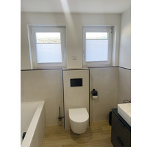 Helles Badezimmer mit Toilette, Waschbecken, Badewanne und zwei Fenstern mit Plissees