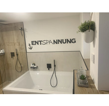 Badezimmer mit Badewanne, Dusche, Wanddekoration mit der Aufschrift Entspannung und einer Pflanze