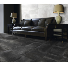 Wohnzimmer mit dunklem Sofa, Lampen und Fliesen